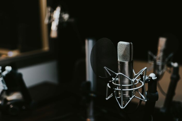 Fotografie eines Mikrofons im dunklen Raum eines Studios.