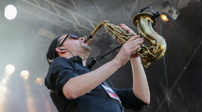 Fotografie eines Künstlers auf der Bühne mit Saxofon.